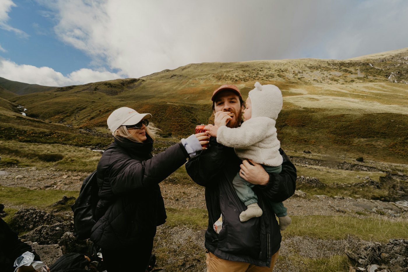 Parents sharing a snack with their baby on a mountain walk