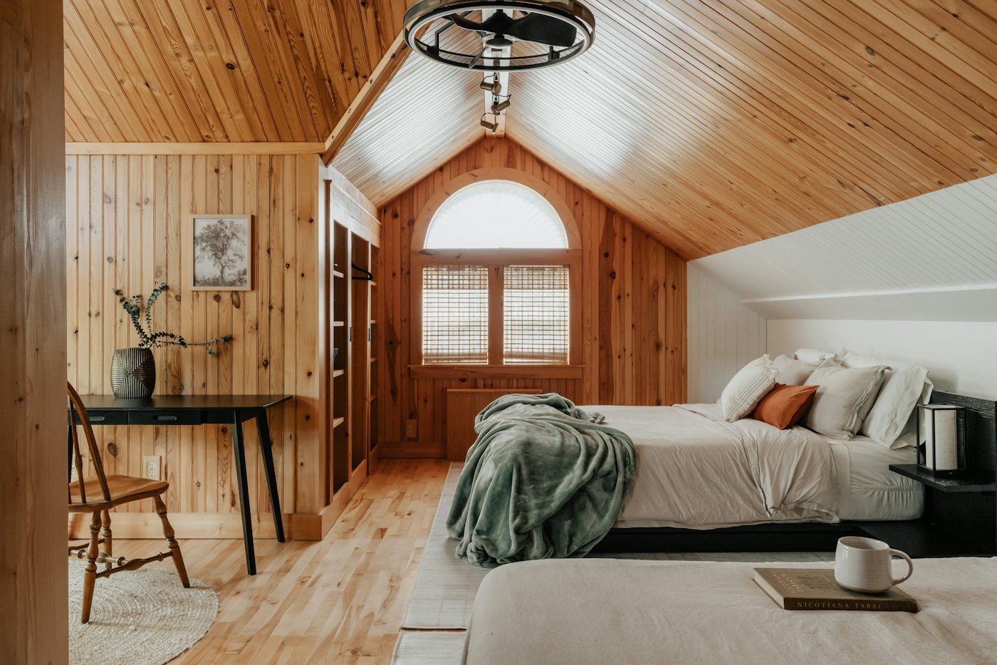 Attic bedroom with pine-clad sloping ceiling, arched window and two beds
