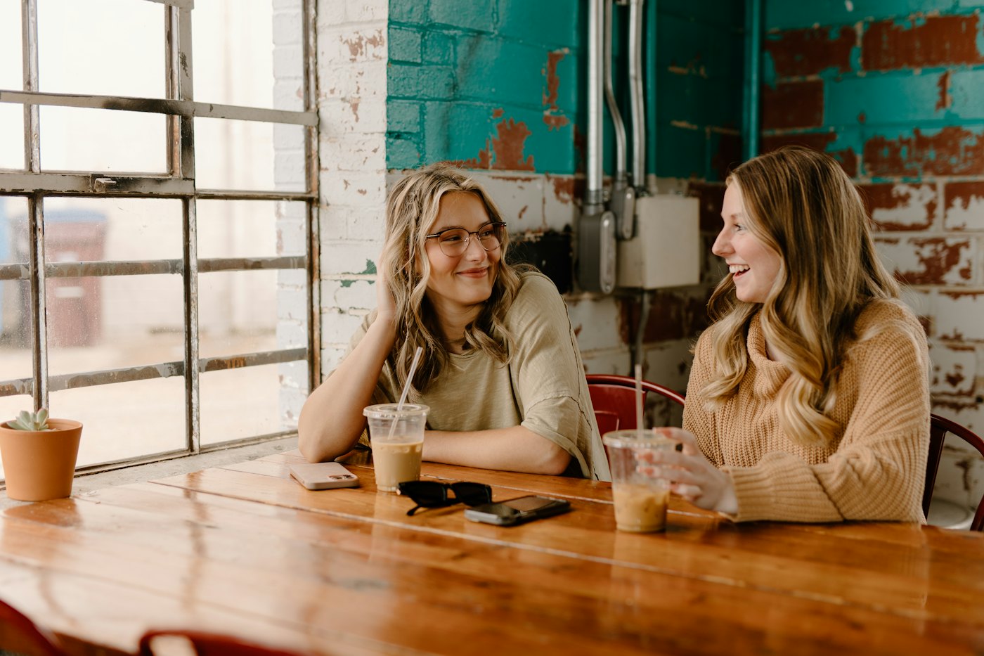 Two women chatting at a wooden table