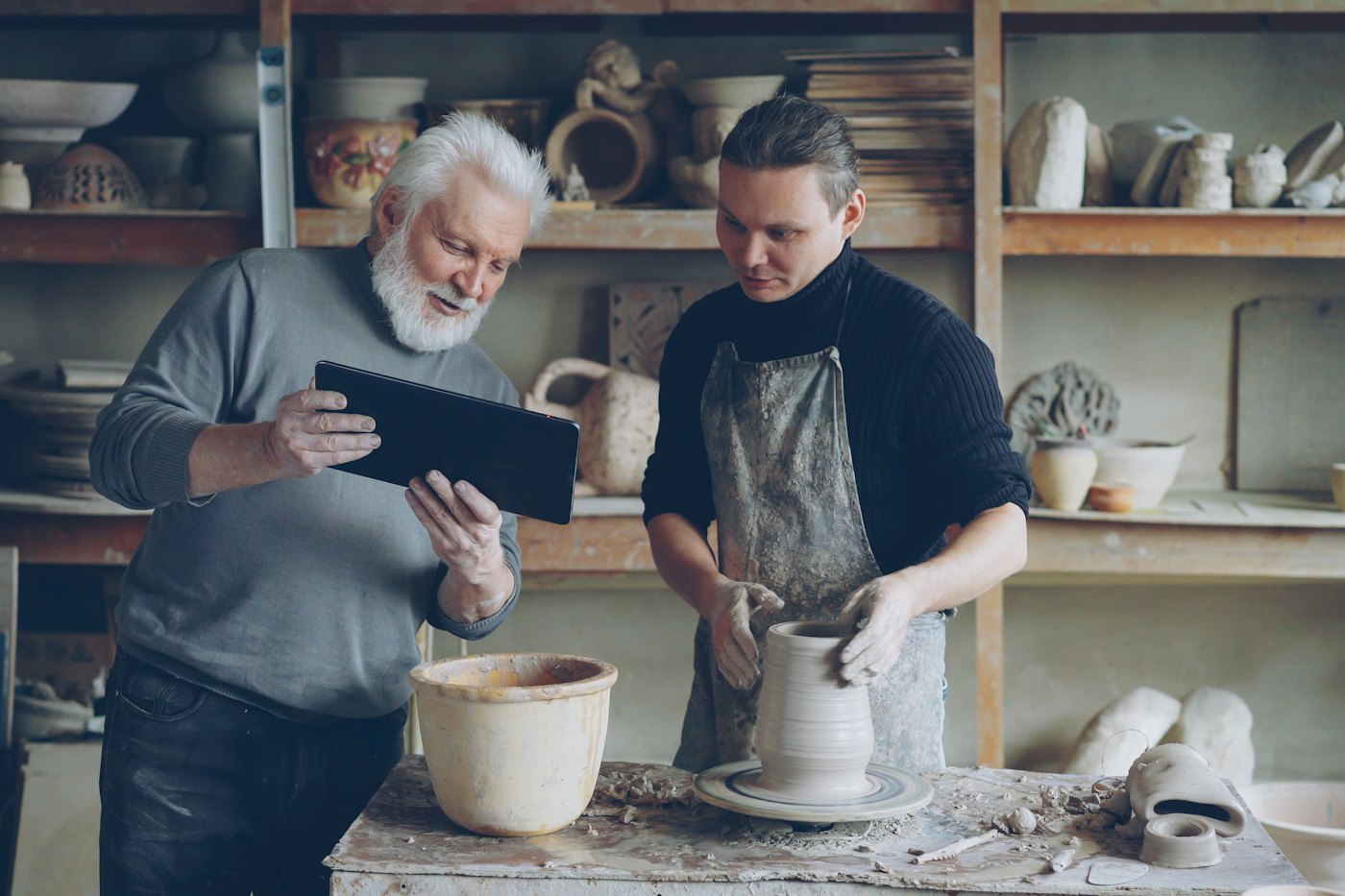 Marek guiding a student's hands at the pottery wheel